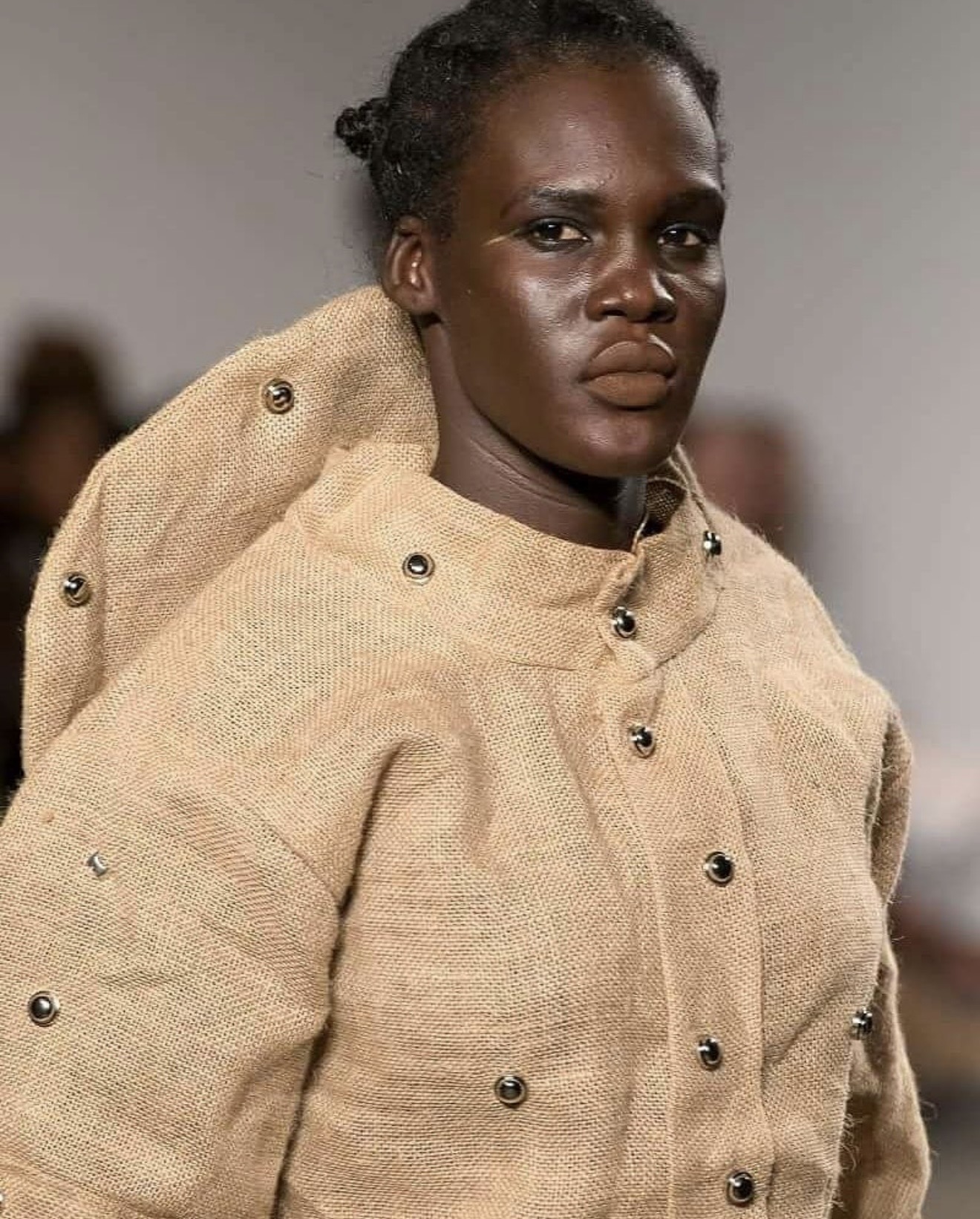 Close-up portrait of male model in oversized sisal sack jacket with metal stud collar detail — menswear